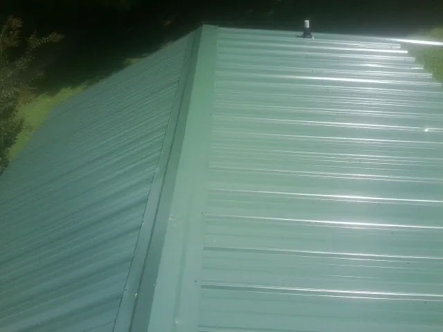 New green metal panels meeting at the ridge of a roof — Flat Roof Repair work by our crew in Canyon Creek