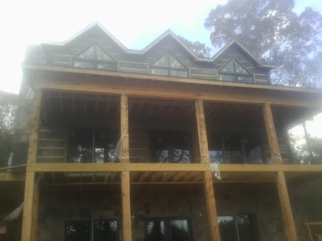 Dormers and porch framing on a large log home under construction — Roof Coating work by our crew in Canyon Creek