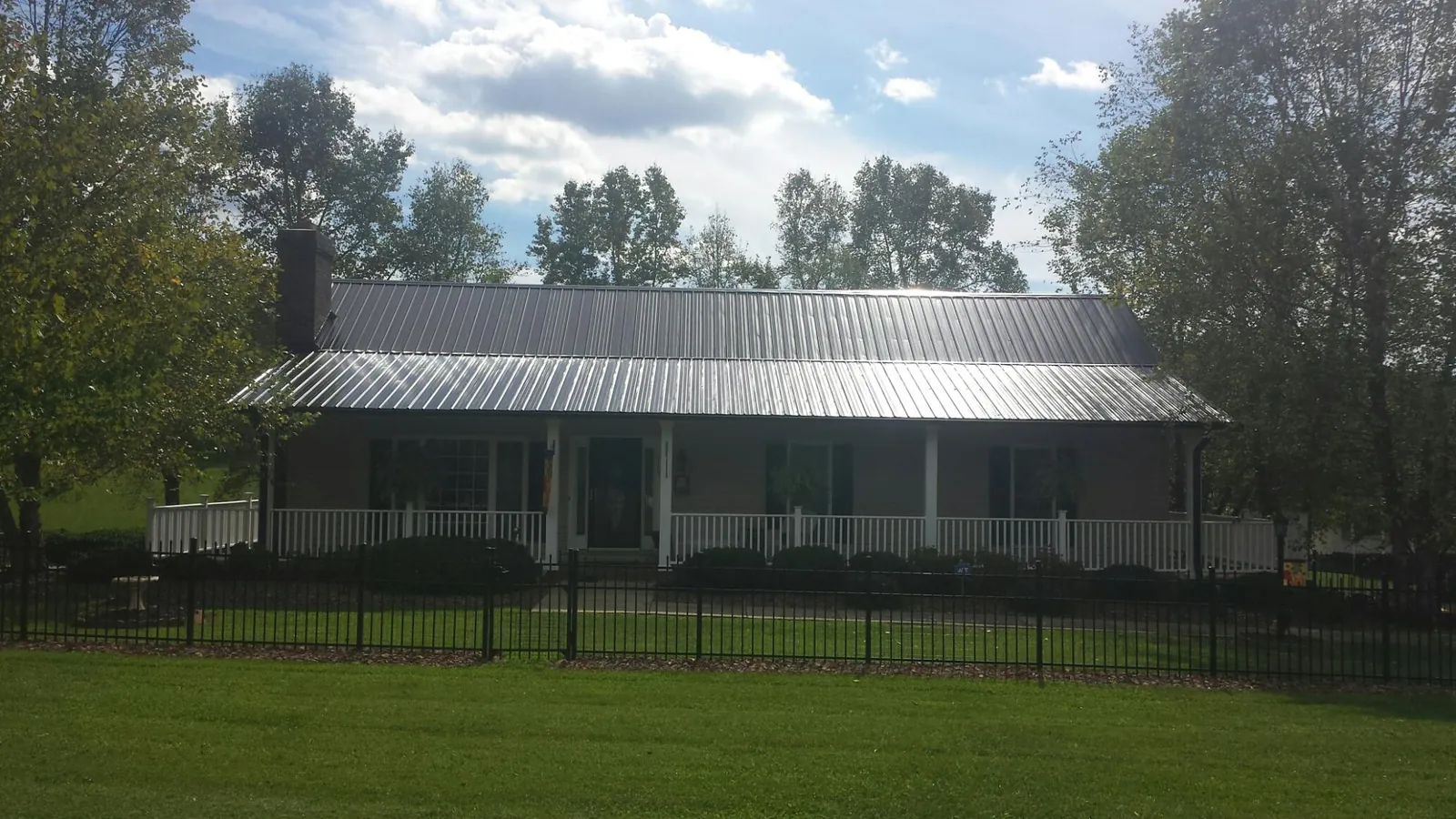 Gray metal roof on a brick ranch with a full width front porch — Gutter Guard Installation work by our crew in Canyon Creek