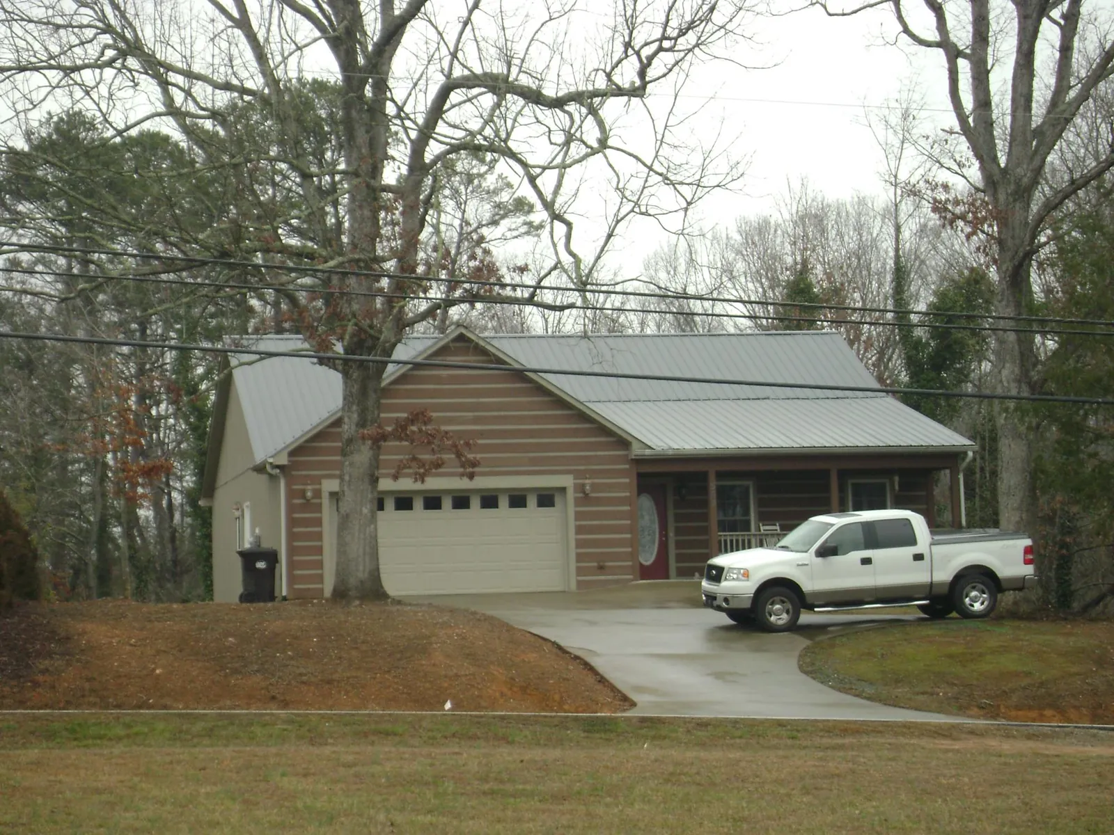 Gray metal roof on a log sided house with an attached two car garage in Canyon Creek