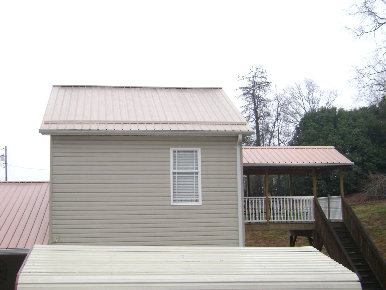 Tan metal roofs on a two story addition and attached porch, from a Roof Replacement job in Canyon Creek
