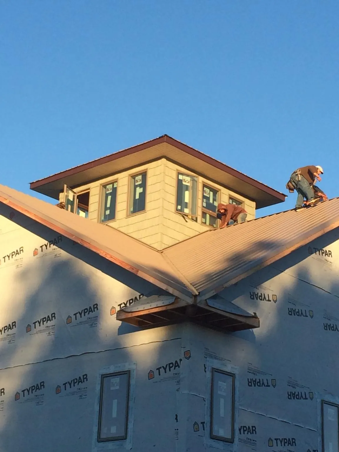 Roofers working around a rooftop cupola on a new metal roof at sunset — Roof Waterproofing in Canyon Creek by Roofing Brothers